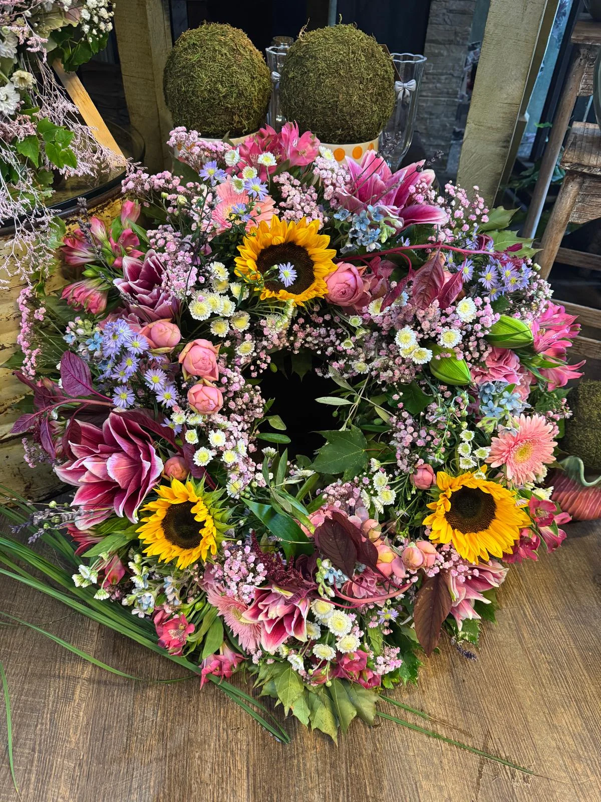 Trauerkranz mit Sonnenblumen, rosa Rosen und violetten Blüten von Eva Blumen